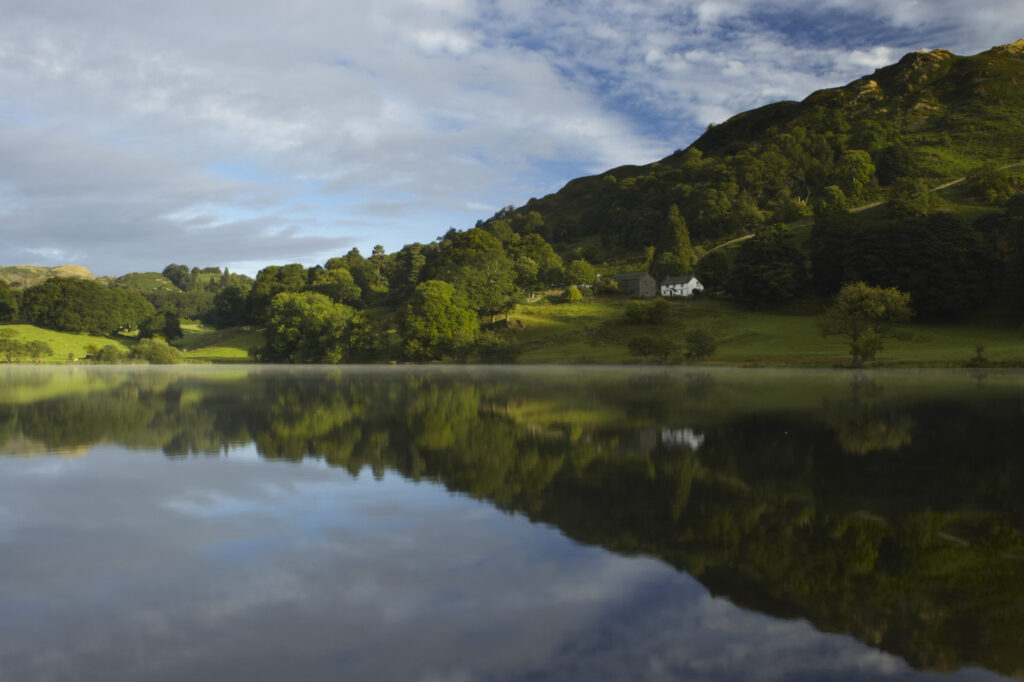 England, Cumbria, Lake District National Park Reflections of typical lake district scenary in the still waters of Loughrigg Tarn