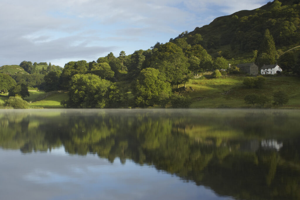 England, Cumbria, Lake District National Park Reflections of typical lake district scenary in the still waters of Loughrigg Tarn
