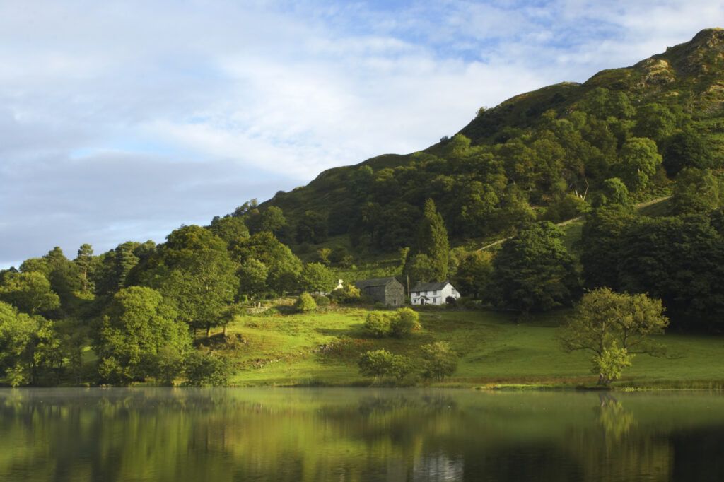 England, Cumbria, Lake District National Park Reflections of typical lake district scenary in the still waters of Loughrigg Tarn