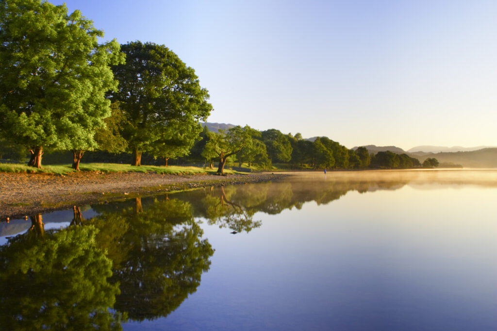 England, Cumbria, Lake District National Park. Dawn looking across the still waters of Coniston Water, within the Lake District National Park.