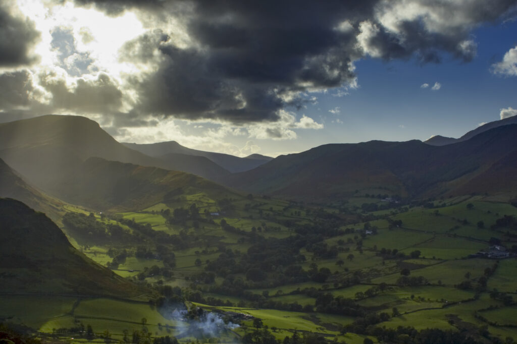 England, Cumbria, Lake District National Park. A shaft of light breaks through storm clouds above the north west lakes.