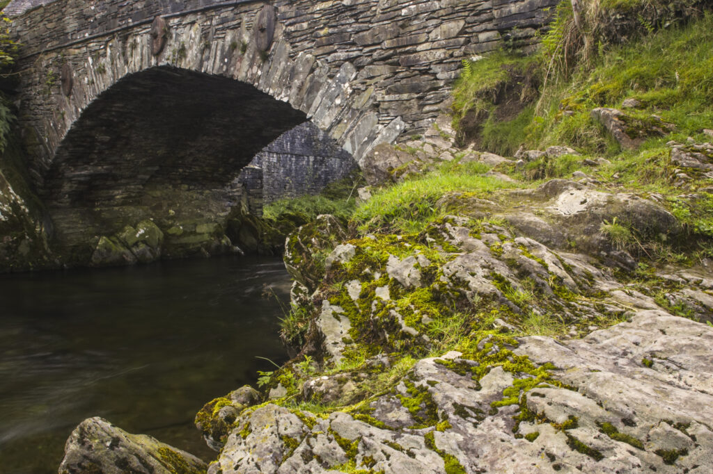 England, Cumbria, Lake District National Park. An old stone bridge stretching over the river near Elterwater.
