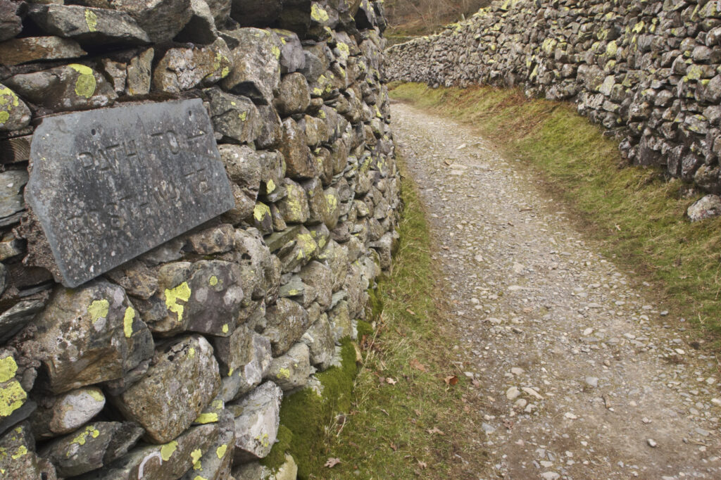 England, Cumbria, Lake District National Park. Public footpath running between dry stone walls near Stonethwaite in Borrowdale.