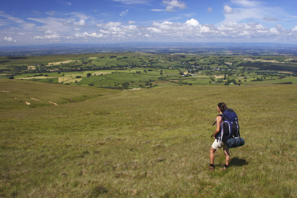 England, Cumbria, Lake District National Park. A hikers enjoys a break admiring the scenery visible from the slopes of High Peak