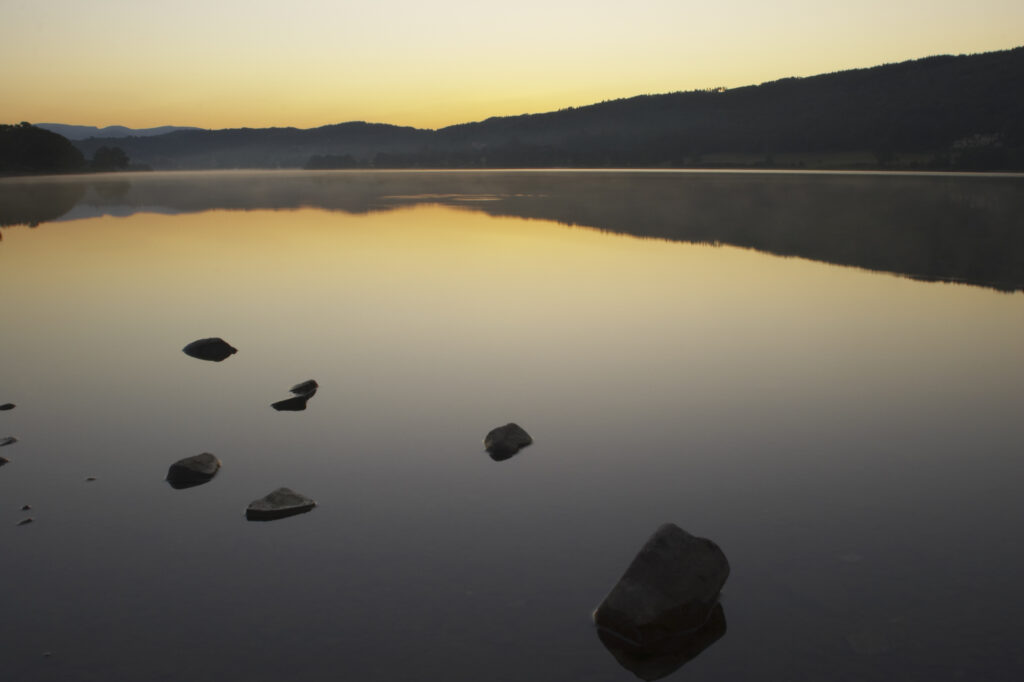 England, Cumbria, Lake District National Park. Dawn looking across the still waters of Coniston Water, within the Lake District National Park.
