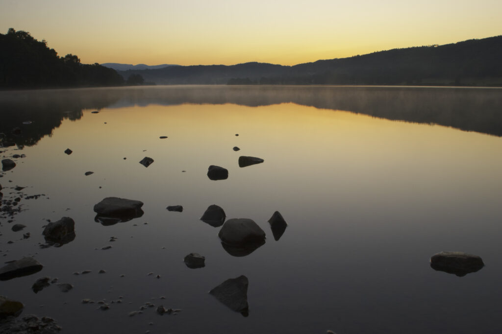 England, Cumbria, Lake District National Park. Dawn looking across the still waters of Coniston Water, within the Lake District National Park.