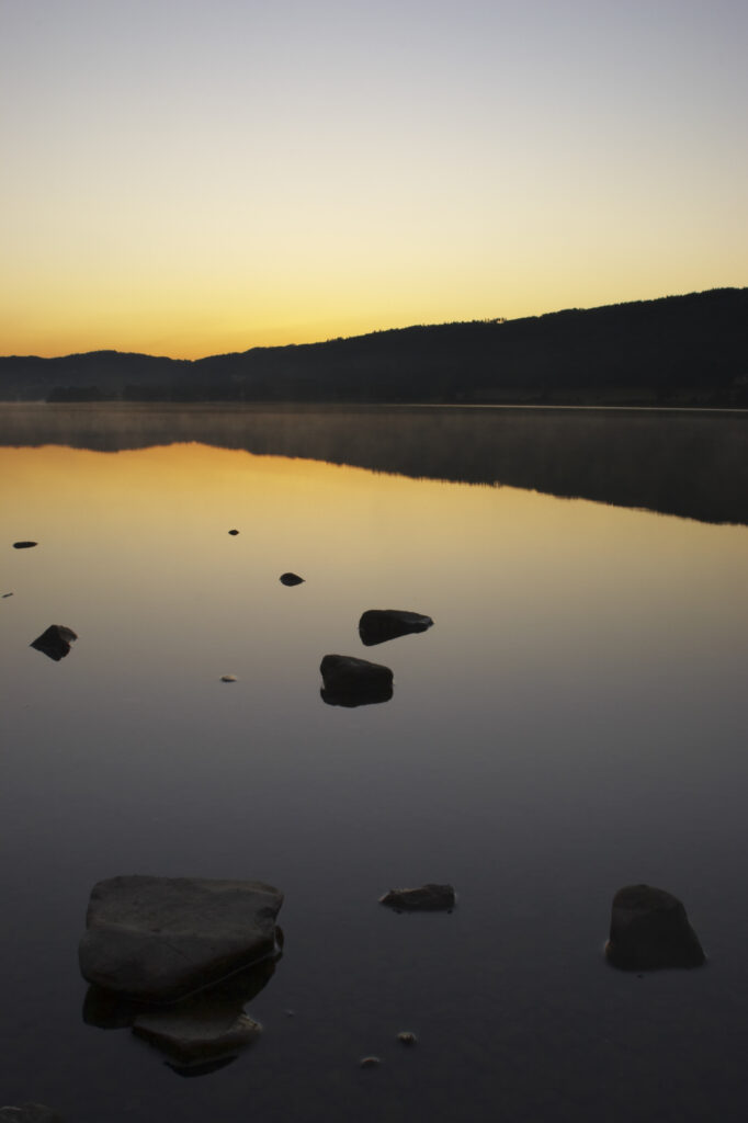 England, Cumbria, Lake District National Park. Dawn looking across the still waters of Coniston Water, within the Lake District National Park.
