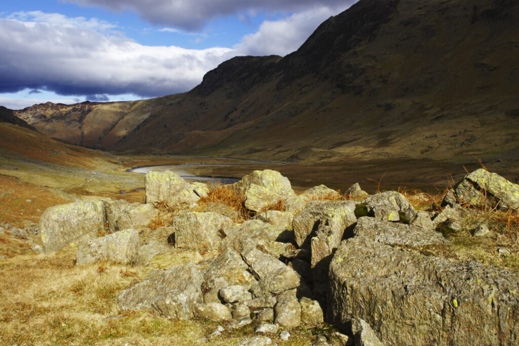 England, Cumbria, Lake District National Park. Brief shafts of sun illuminate the surrounding peaks of the Langstrath Valley.