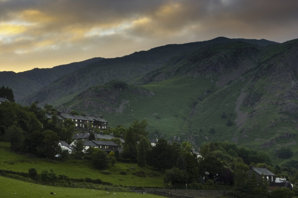England, Cumbria, Lake District National Park. Lakeland homes in Coniston against an impressive mountain backdrop.