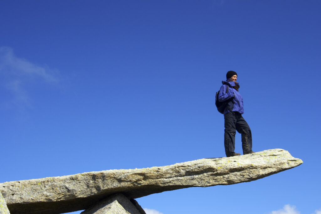 Wales, Caernarfonshire, Snowdonia National Park. Female hiker admiring the landscape from the Cantilever stone, near the peak of the Glyder Fach mountain.