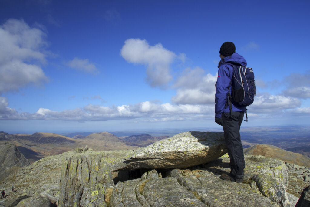 Wales, Caernarfonshire, Snowdonia National Park. Female hiker admiring the view from the summit of the Glyder Fach mountain.