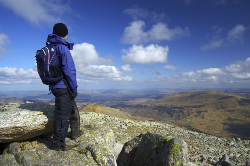 Wales, Caernarfonshire, Snowdonia National Park. Female hiker admiring the view from the summit of the Glyder Fach mountain.
