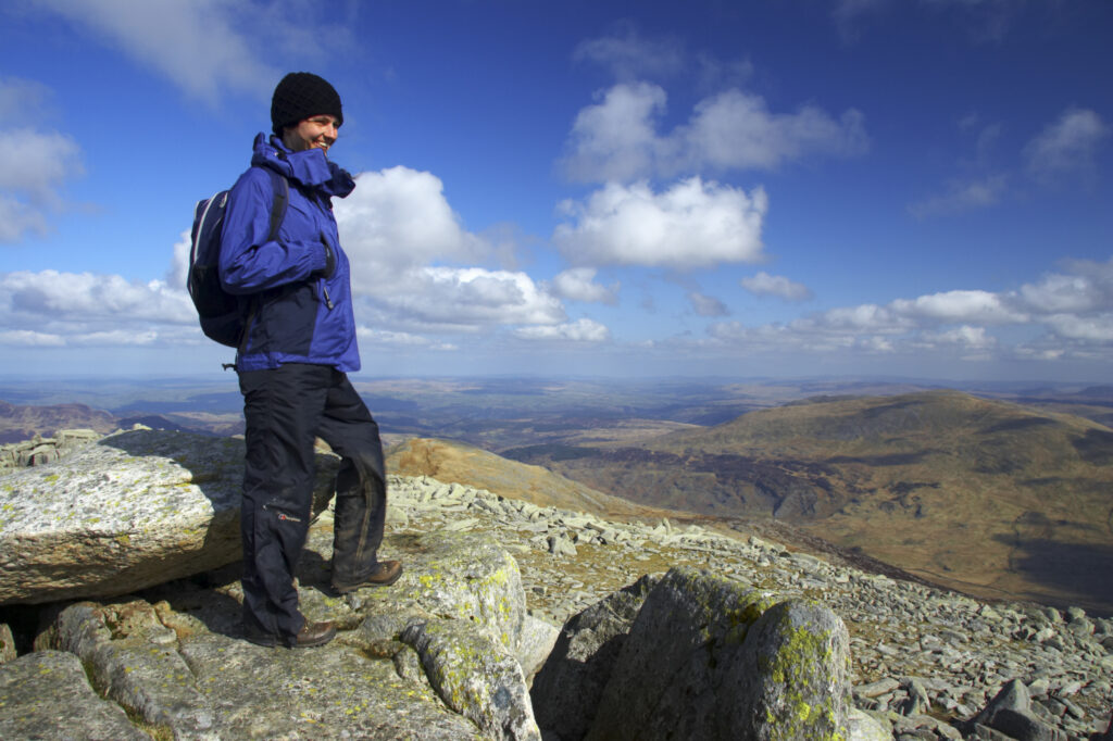 Wales, Caernarfonshire, Snowdonia National Park. Female hiker admiring the view from the summit of the Glyder Fach mountain.