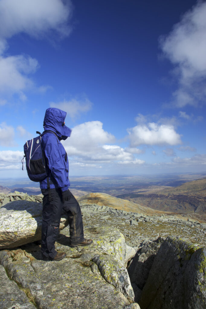 Wales, Caernarfonshire, Snowdonia National Park. Female hiker admiring the view from the summit of the Glyder Fach mountain.