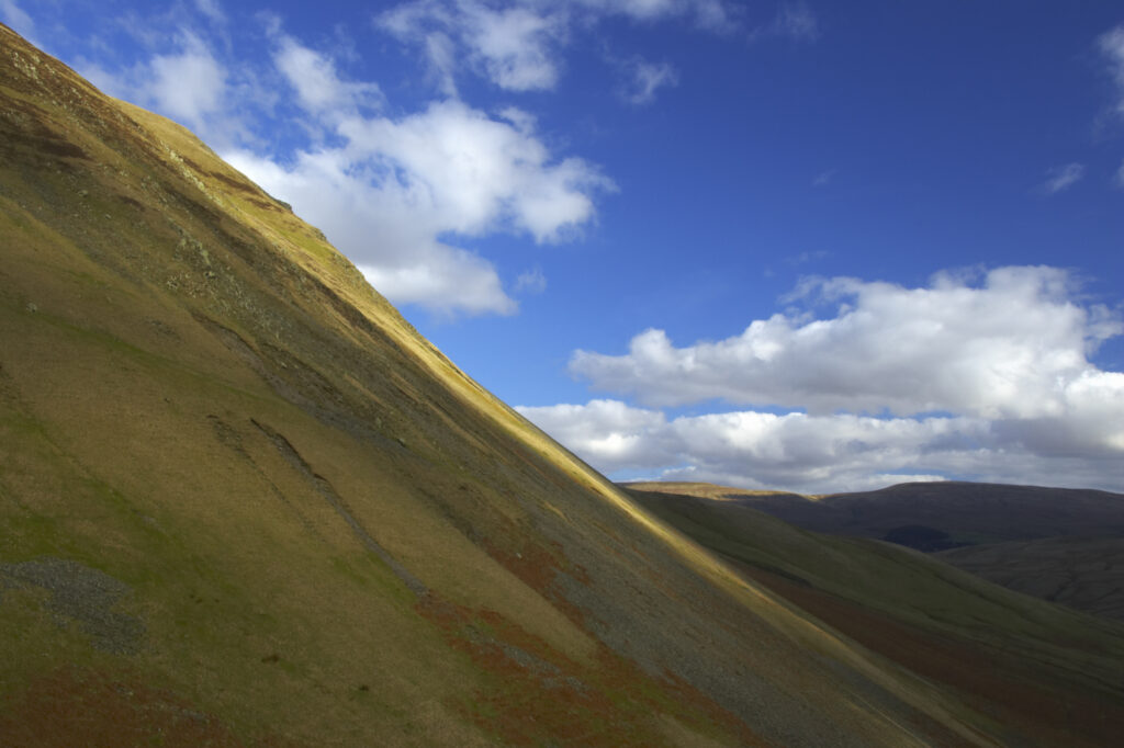 England, Cumbria, Yorkshire Dales National Park. A shaft of light illuminates the hills of the park, located to the north east of the town of Sedbergh. Viewed from the Howgills.
