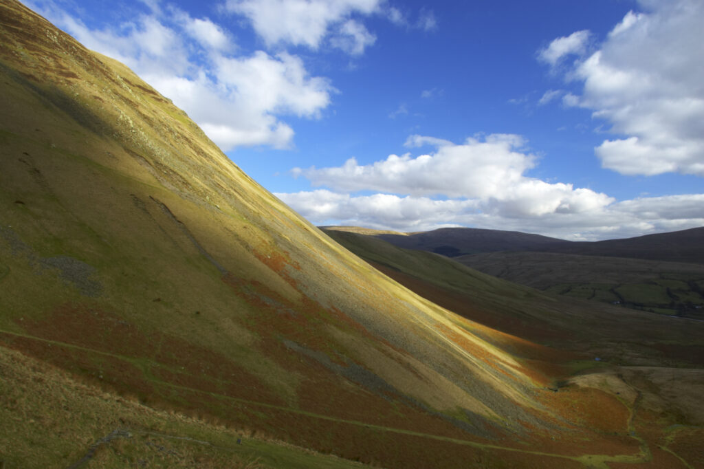 England, Cumbria, Yorkshire Dales National Park. A shaft of light illuminates the hills of the park, located to the north east of the town of Sedbergh. Viewed from the Howgills.