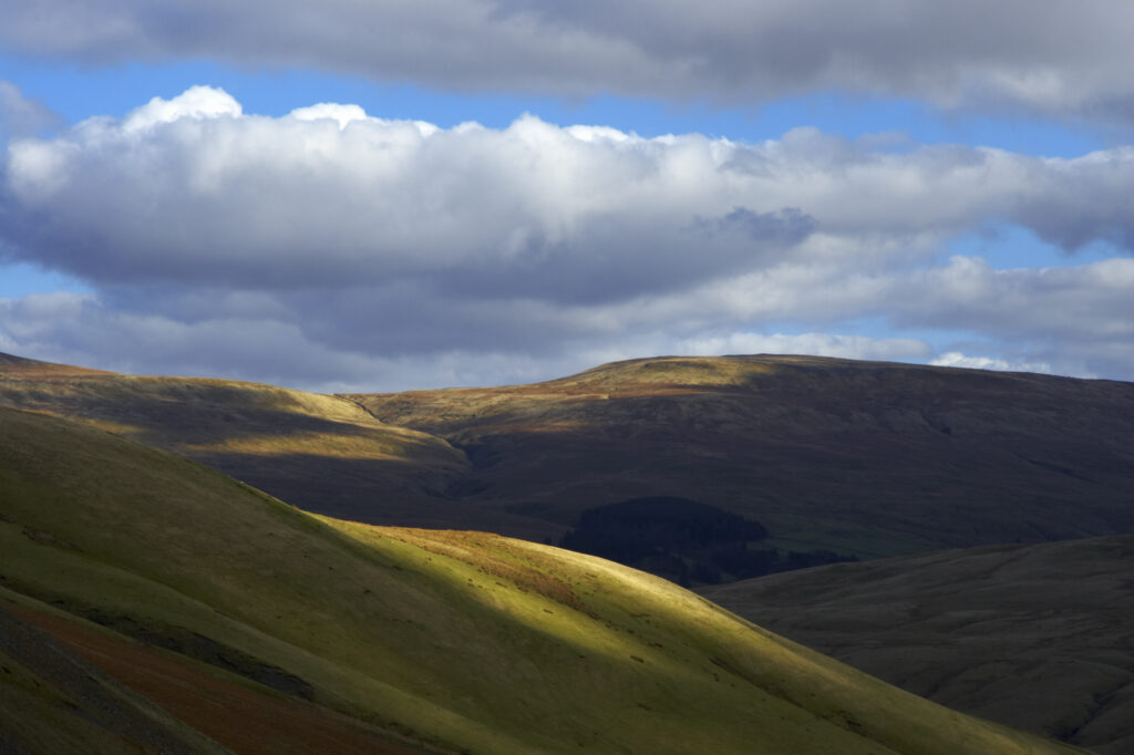 England, Cumbria, Yorkshire Dales National Park. A shaft of light illuminates the hills of the park, located to the north east of the town of Sedbergh. Viewed from the Howgills.