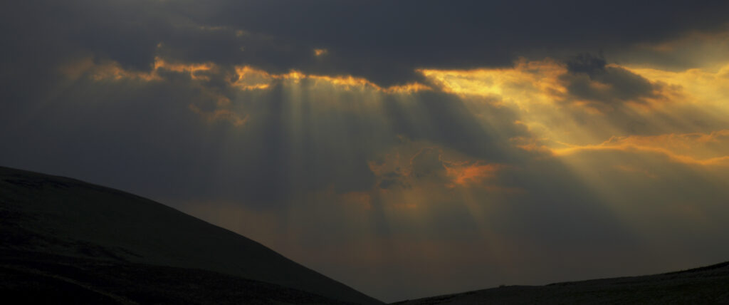 Scotland, Scottish Borders, The Pennine Way. Dramatic light breaking through clouds above the Scottish Uplands, viewed from the low level route of the Pennine Way near Kirk Yetholm.