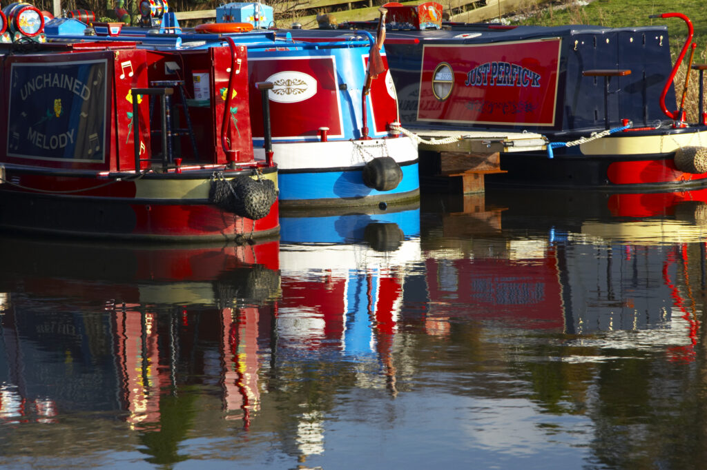 England, Lancashire, Galgate. Reflections of boats moored on canal near Galgate and Lancaster.