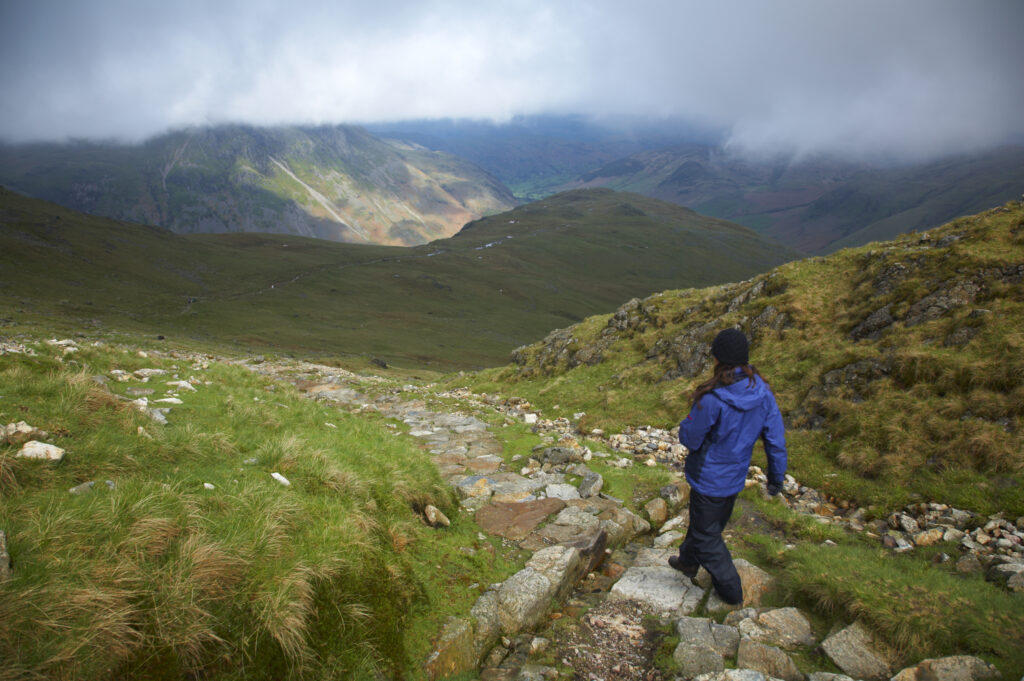 England, Cumbria, Lake District National Park. Hiker descending from tarn towards Dungeon Ghyll in the Great Langdale Valley
