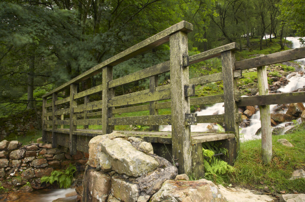 England, Cumbria, Lake District National Park. Wooden bridge stretching over rapids near Lake Buttermere in Cumbria.