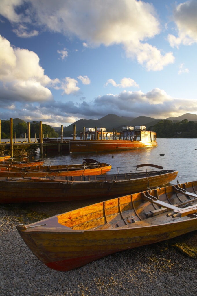England, Cumbria, Lake District National Park. Wooden rowing boats and Derwent Water cruise ship moored at Jetty on Derwentwater