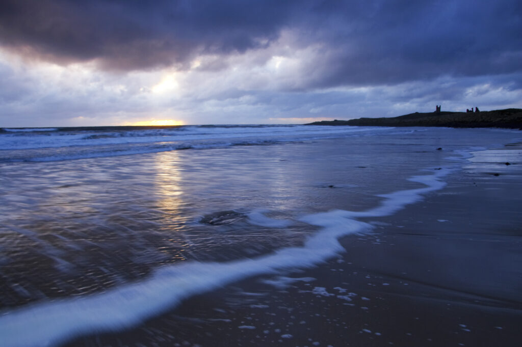 England, Northumberland, Embleton Bay. A dramatic sunrise over the north sea and Embleton Bay near Dunstanburgh Castle.