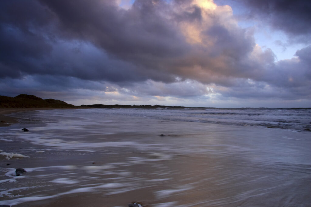 England, Northumberland, Embleton Bay. A dramatic sunrise over the north sea and Embleton Bay near Dunstanburgh Castle.