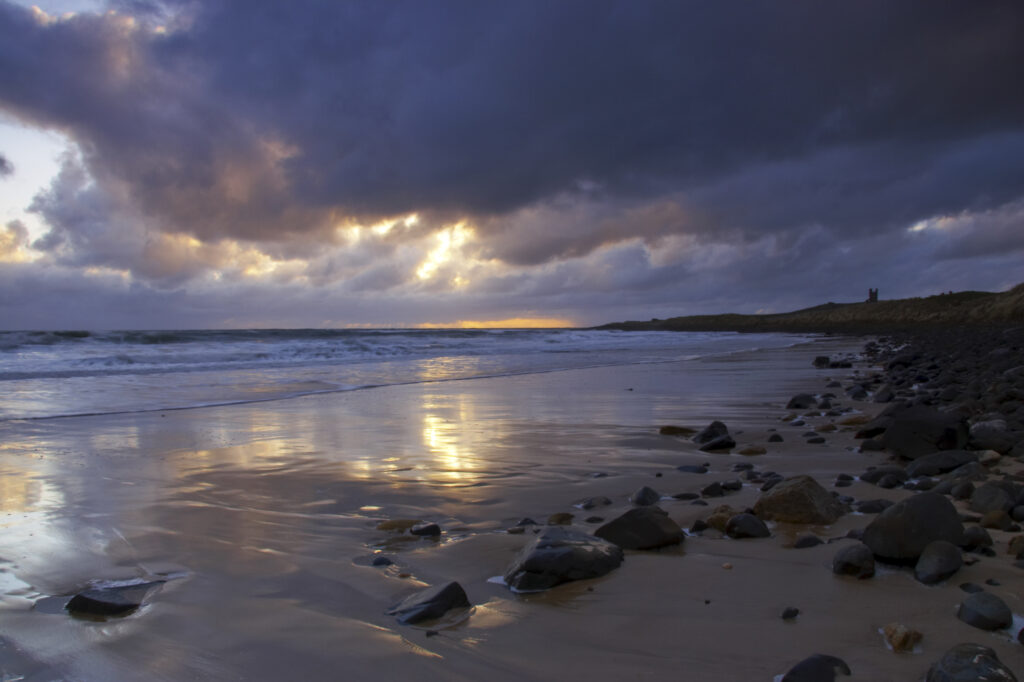 England, Northumberland, Embleton Bay. A dramatic sunrise over the north sea and Embleton Bay near Dunstanburgh Castle.