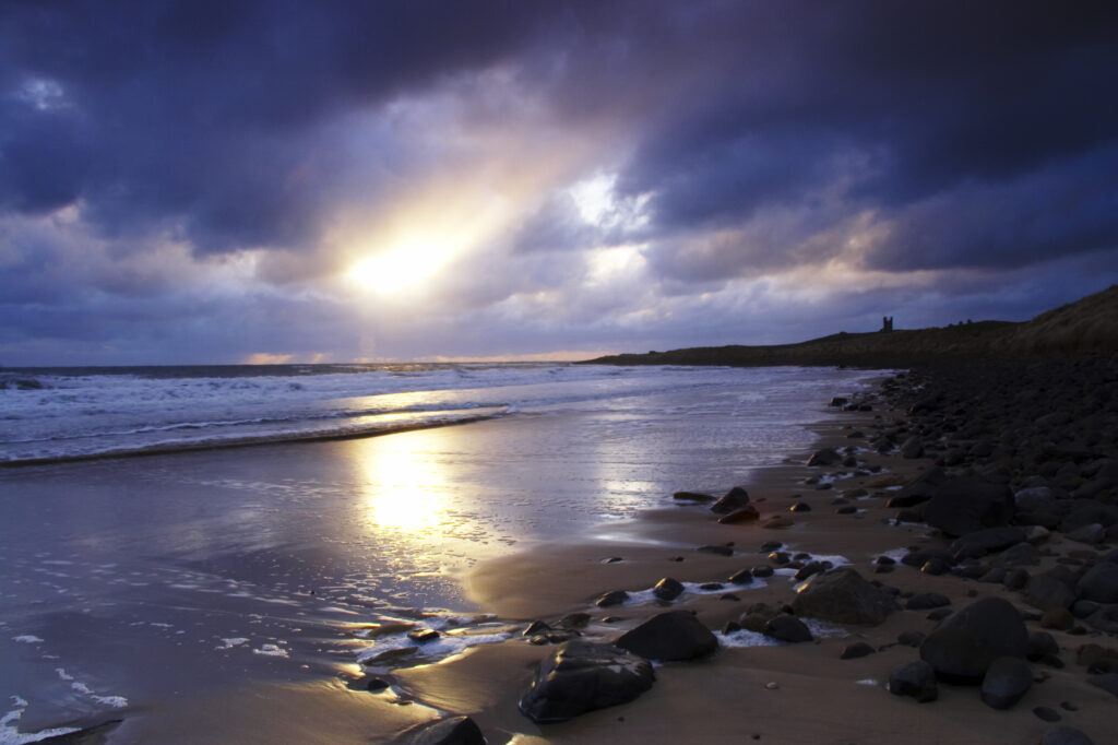 England, Northumberland, Embleton Bay. A dramatic sunrise over the north sea and Embleton Bay near Dunstanburgh Castle.