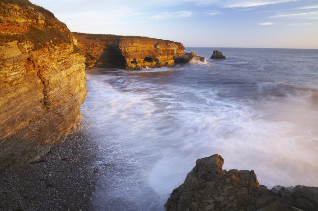 England, Tyne and Wear, Marsden Bay. Early morning light illuminates the crashing waves of the North Sea, near Lizard Point and Marsden Bay.