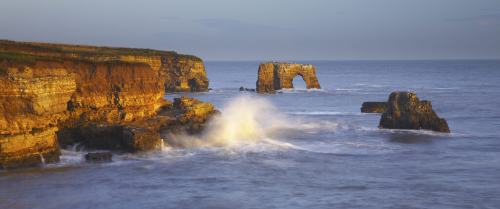 Early morning light illuminates the crashing waves of the North Sea, near Lizard Point and Marsden Bay.