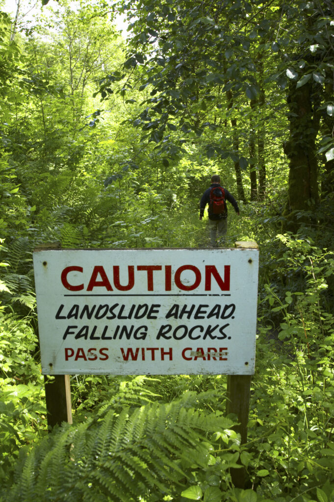 England, Cumbria, Caldbeck. A sign waring of falling rocks in woodland near the village of Caldbeck.