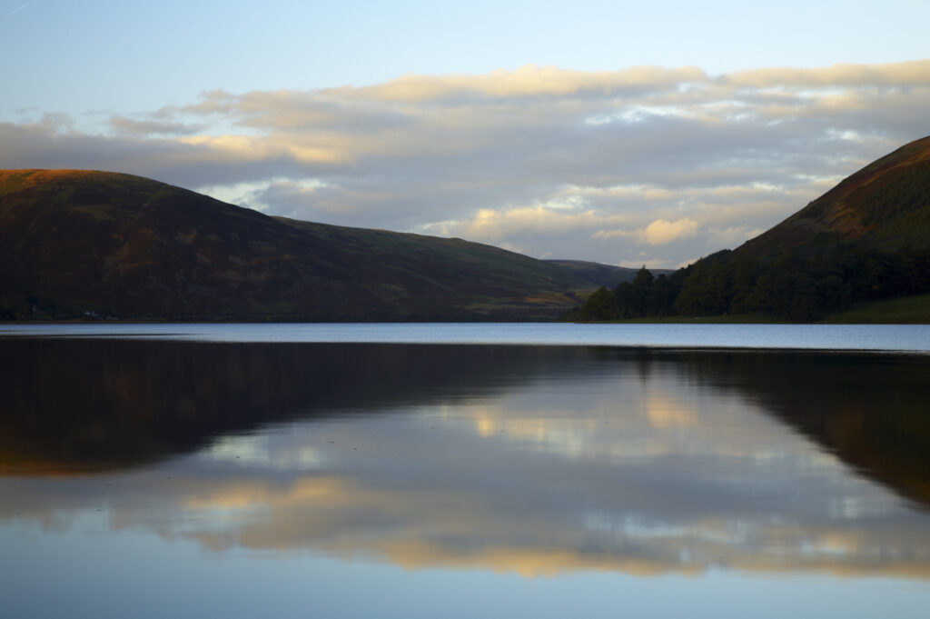 Scotland, Scottish Borders, St Marys Loch. The calm water of the loch reflects the clouds and the hills surrounding St Marys Loch.