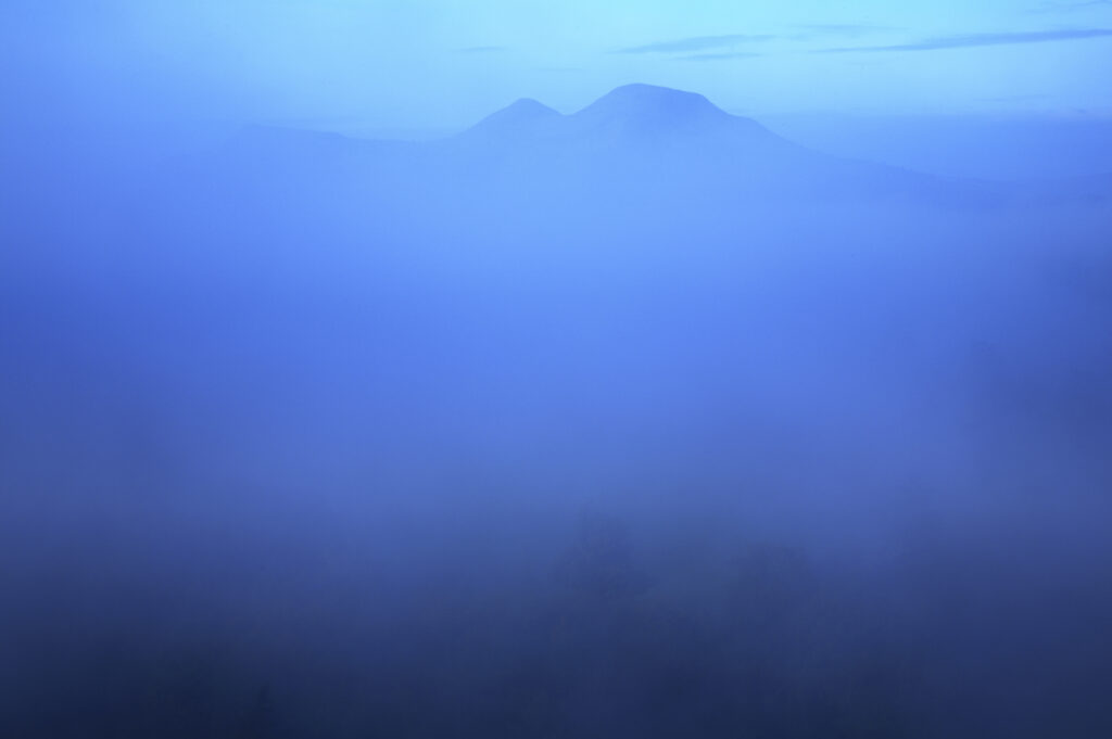 Scotland, Scottish Borders, Melrose. Autumn mists rise from the low lying countryside surrounding the The Eildon Hills, viewed from the famous viewpoint of Scott's View near Newton St Boswells.