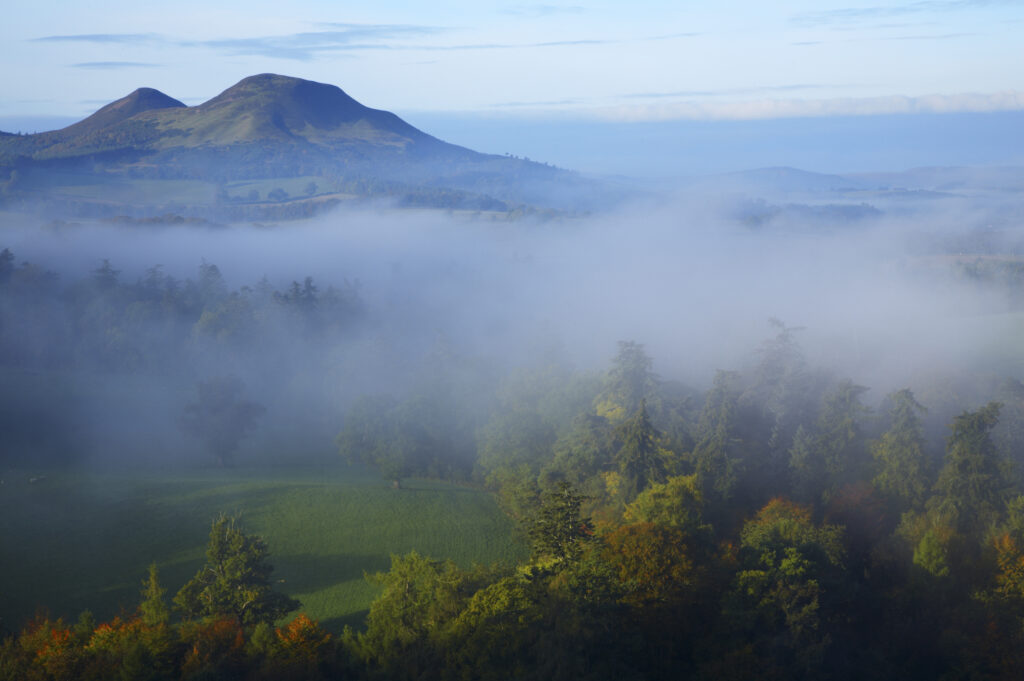 Scotland, Scottish Borders, Melrose. Autumn mists rise from the low lying countryside surrounding the The Eildon Hills, viewed from the famous viewpoint of Scott's View near Newton St Boswells.
