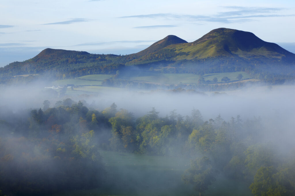 Scotland, Scottish Borders, Melrose. Autumn mists rise from the low lying countryside surrounding the The Eildon Hills, viewed from the famous viewpoint of Scott's View near Newton St Boswells.