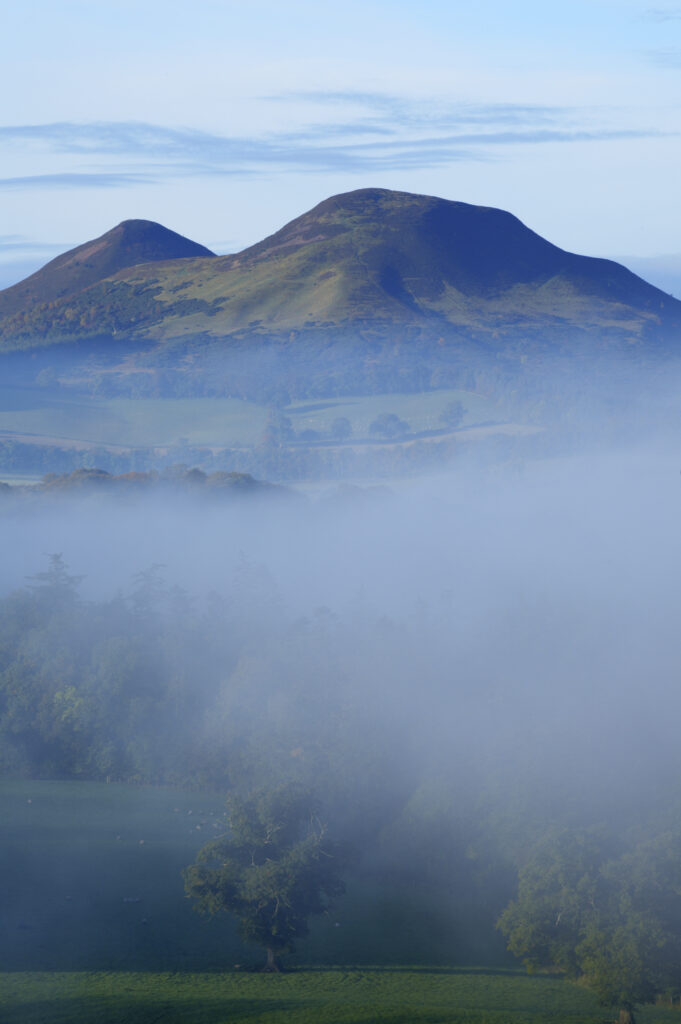 Scotland, Scottish Borders, Melrose. Autumn mists rise from the low lying countryside surrounding the The Eildon Hills, viewed from the famous viewpoint of Scott's View near Newton St Boswells.