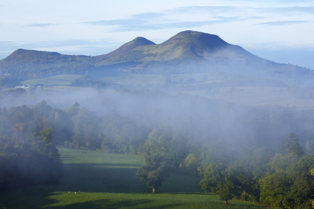 Scotland, Scottish Borders, Melrose. Autumn mists rise from the low lying countryside surrounding the The Eildon Hills, viewed from the famous viewpoint of Scott's View near Newton St Boswells.