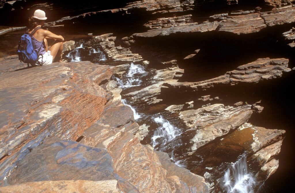 AUSTRALIA, Western Australia, Karajini National Park. Girl bush walker relaxing at the top of the Joffre Falls
