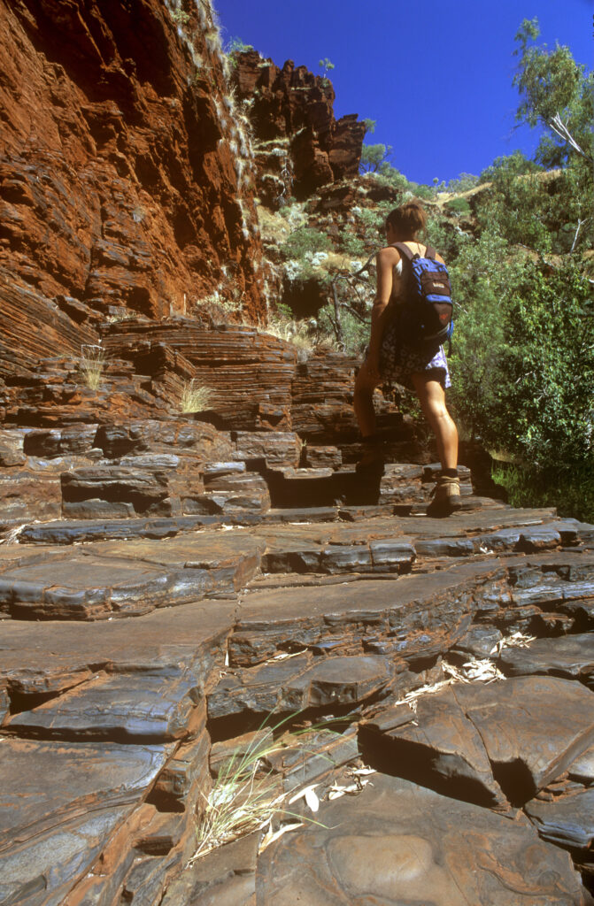 AUSTRALIA, Western Australia, Karajini National Park. Girl bush walker exploring the red terraces of Knox Gorge