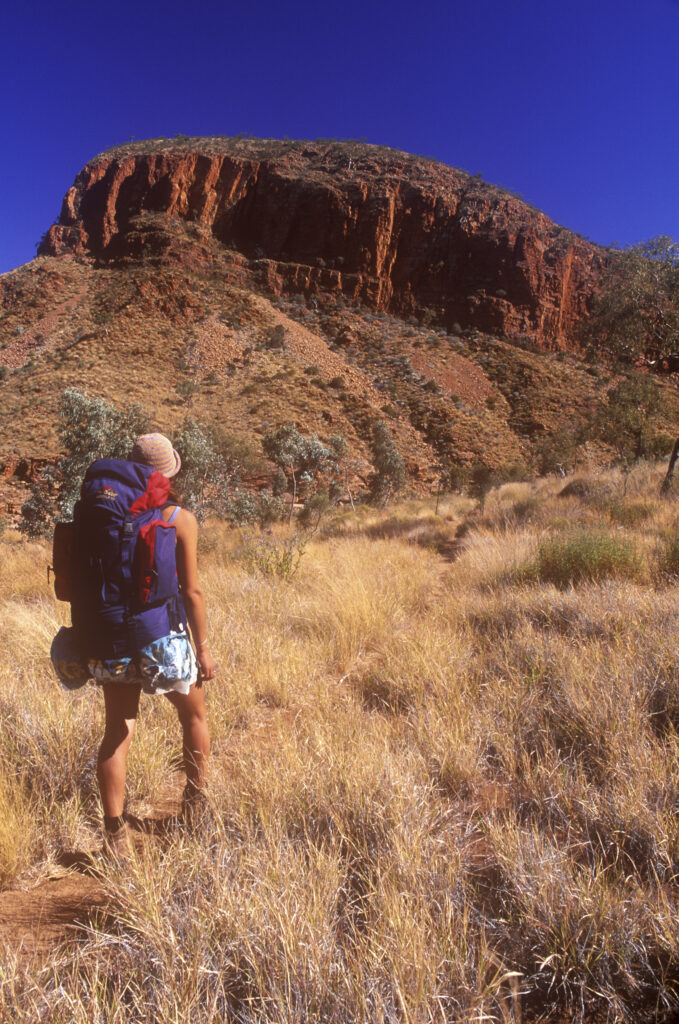 AUSTRALIA, Northern Territory, West MacDonnell National Park. A girl hiking towards the spectacular landscape of the Ormiston Gorge