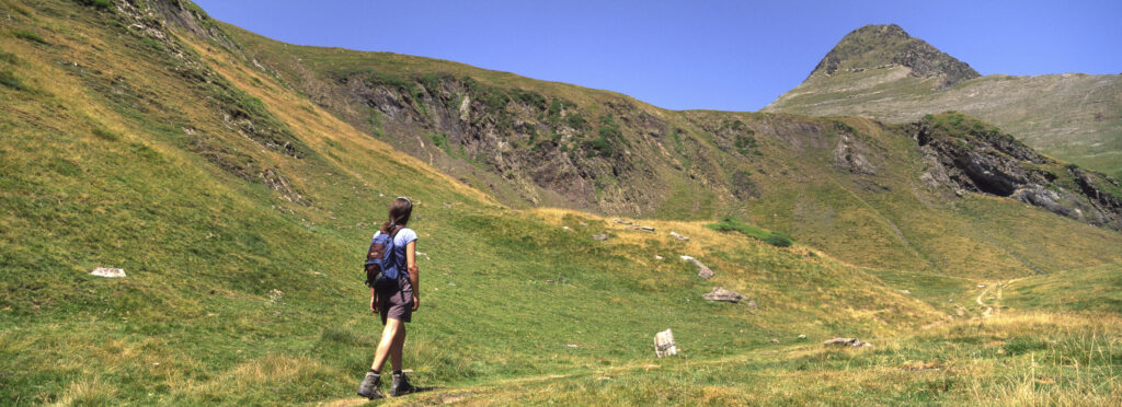 FRANCE, Midi Pyrenees, Pyrenees National Park. Girl walking through the wild landscape of the national park