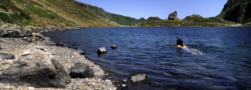 FRANCE, Midi Pyrenees, Pyrenees National Park. Girl swimming in the tranquil waters of the Lac d Ilheou