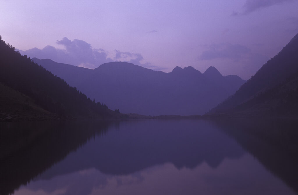 FRANCE, Midi Pyrenees, Pyrenees National Park. Dusk cast a pinkish glow to the lake and surrounding landscape of Lac De Gaub