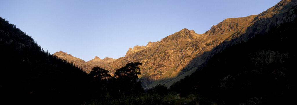 FRANCE, Midi Pyrenees, Pyrenees National Park. Early morning light illuminates the peaks and woodlands of the Pont d Espagne
