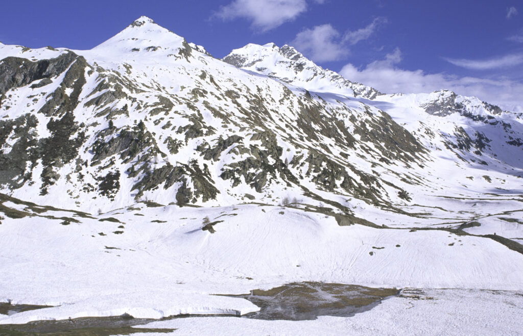 ITALY, Valle d'Aosta, Gran Paradiso National Park. Snow remains well into spring in the peaks of the mountain landscape of the western Alps and the valley near Bardoney.