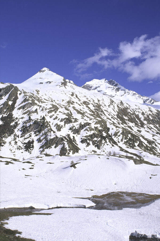 ITALY, Valle d'Aosta, Gran Paradiso National Park. Snow remains well into spring in the peaks of the mountain landscape of the western Alps and the valley near Bardoney.