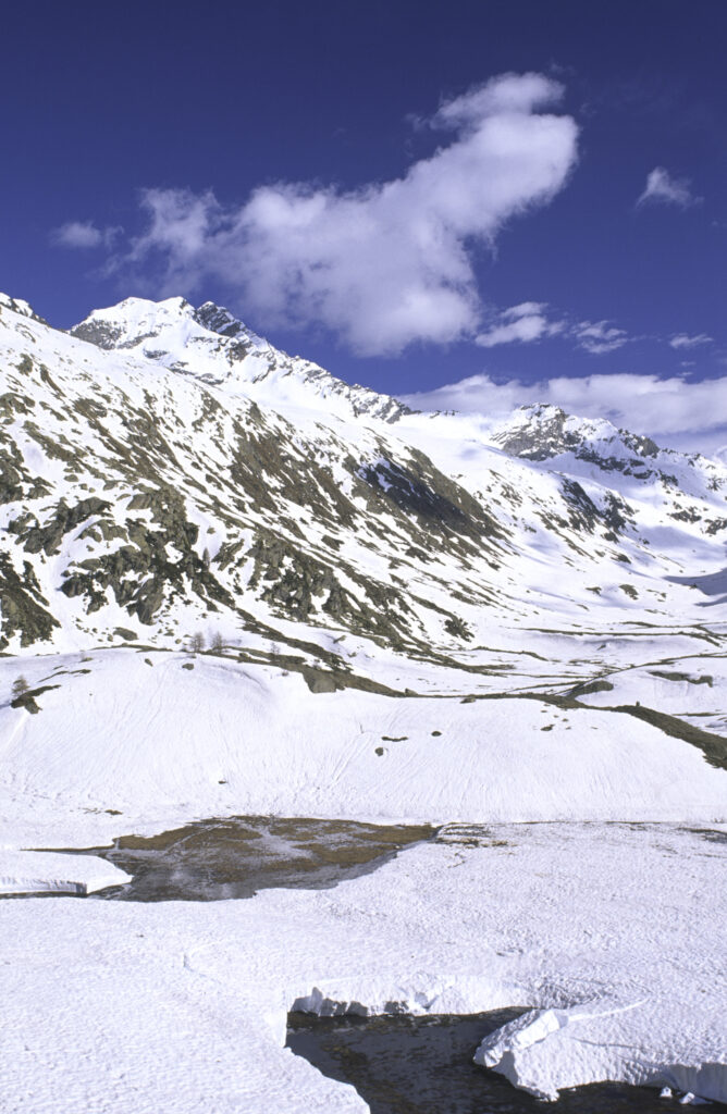 ITALY, Valle d'Aosta, Gran Paradiso National Park. Snow remains well into spring in the peaks of the mountain landscape of the western Alps and the valley near Bardoney.