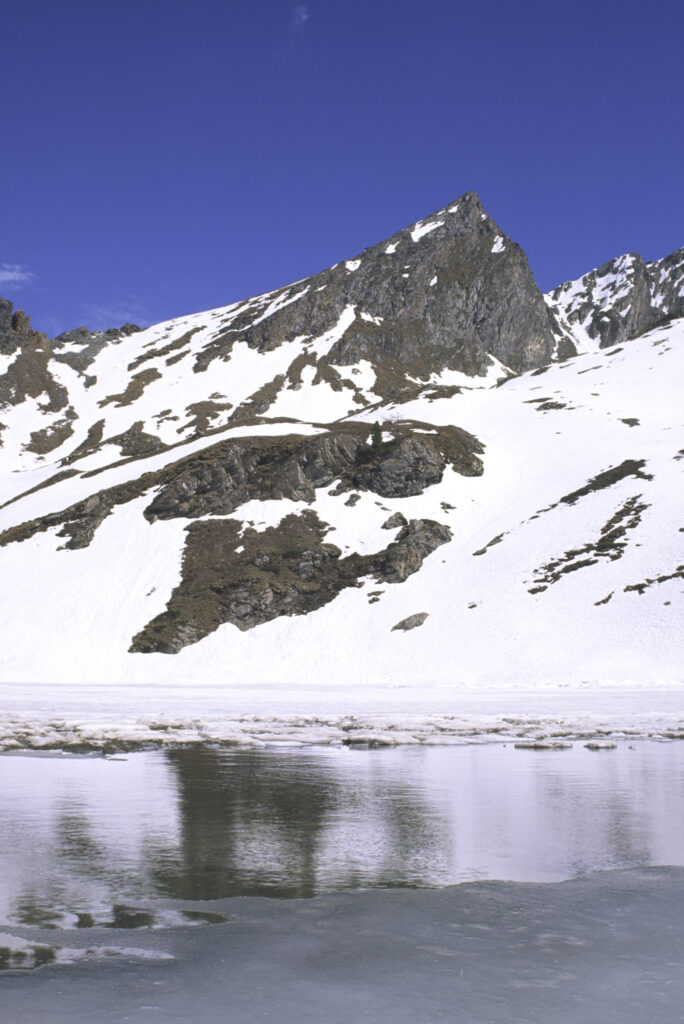 ITALY, Valle d'Aosta, Gran Paradiso National Park. The ice covered Lake Loie (lago di loie) in the peaks of the mountain landscape of the western Alps above the Lillaz valley.